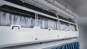 An inside view of an air conditioner showing a ice on the ac unit inside with water buildup and dirty coils.