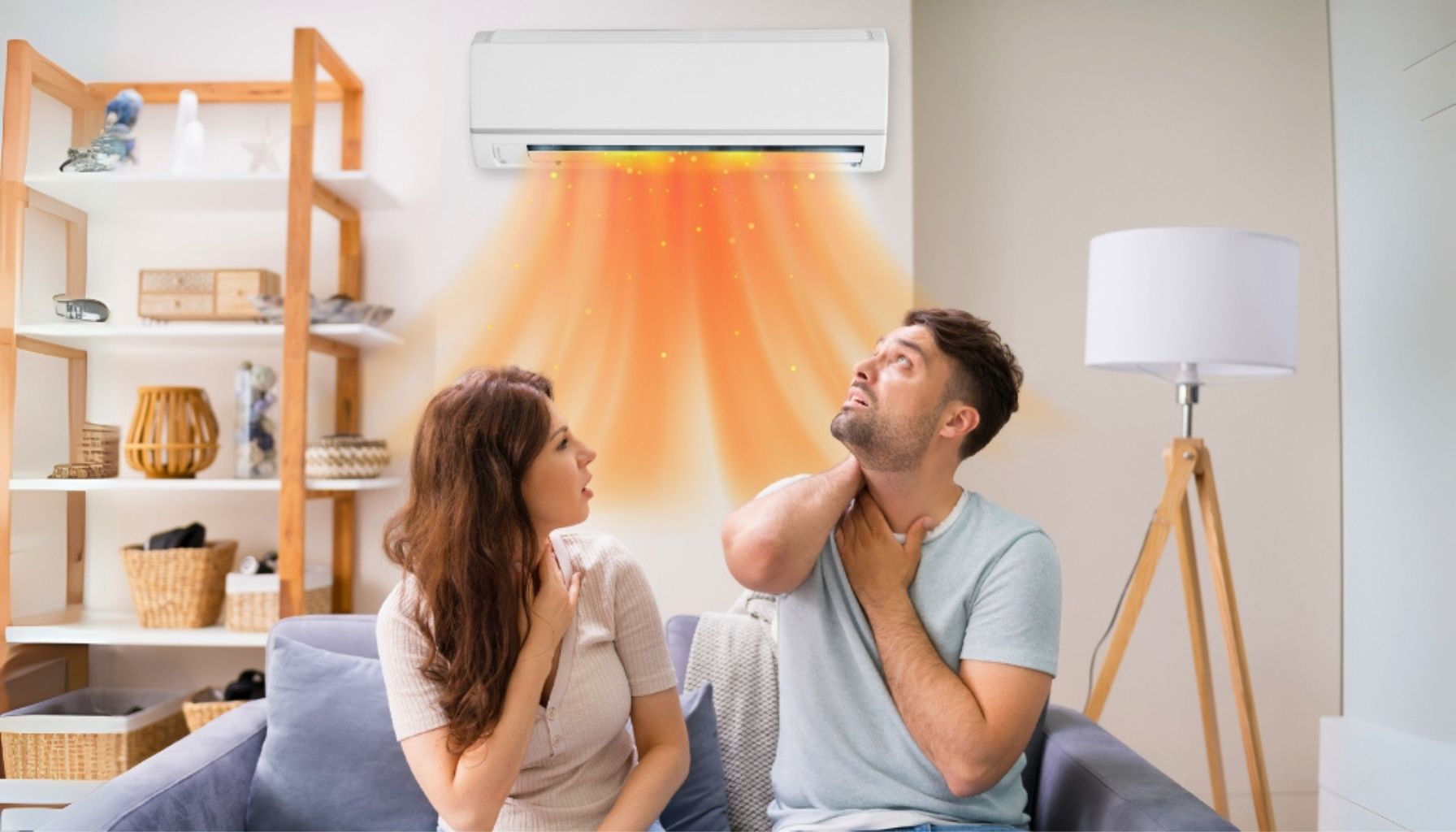 A couple sitting on a couch, feel warm air from a wall-mounted air conditioning because your ac not blowing cold air unit in a cozy living room setting.